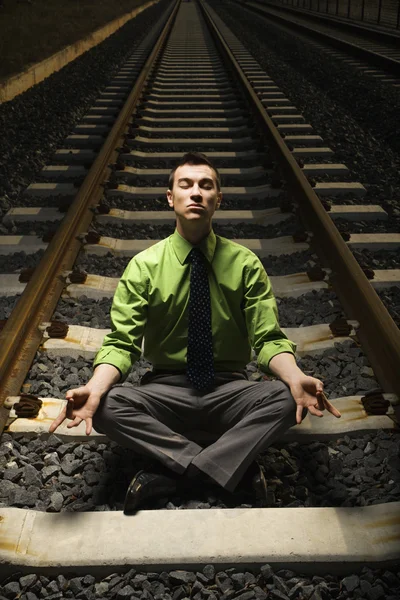 Бизнесмен медитирует на железнодорожных путях . — стоковое фото