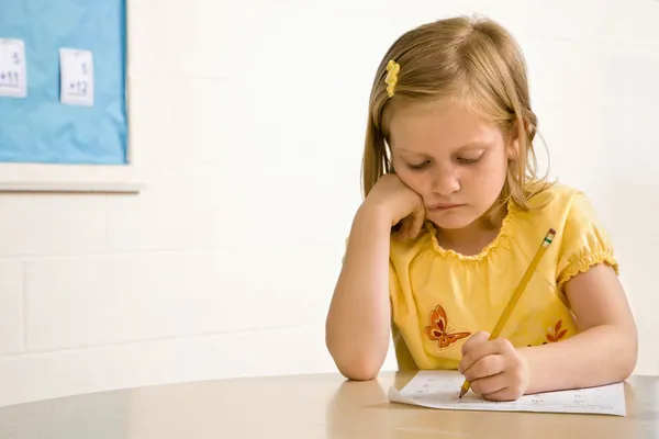 年轻女孩在教室里在纸张上书写 — 图库照片