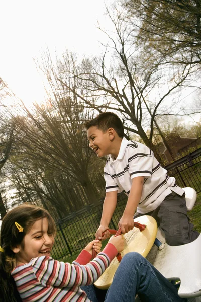 Ung flicka och pojke spelar på gungbräda — Stockfoto