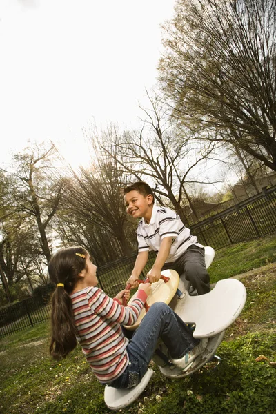 Giovane ragazza e ragazzo giocare su altalena — Foto Stock