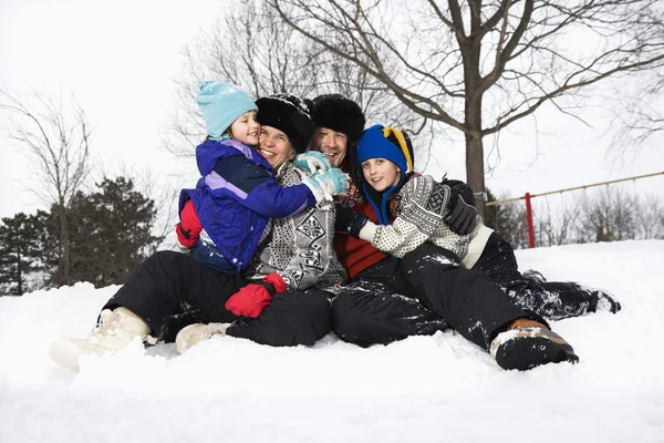 坐在雪中的家庭. 图库照片