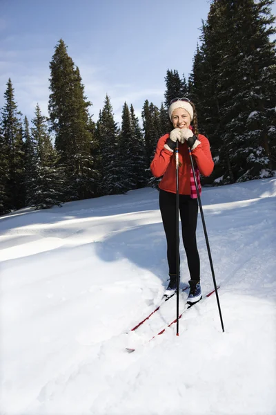 Θηλυκό χιόνι skiier κλίση σε πόλους και χαμογελαστός Εικόνα Αρχείου