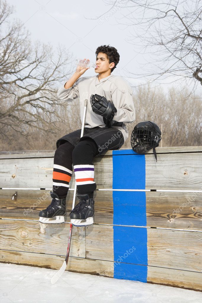Hockey boy drinking water.