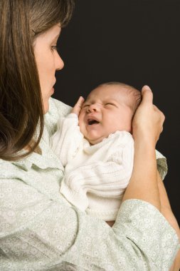 Mother holding crying baby. clipart