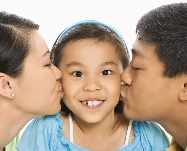 Parents kissing girl. Royalty Free Stock Images