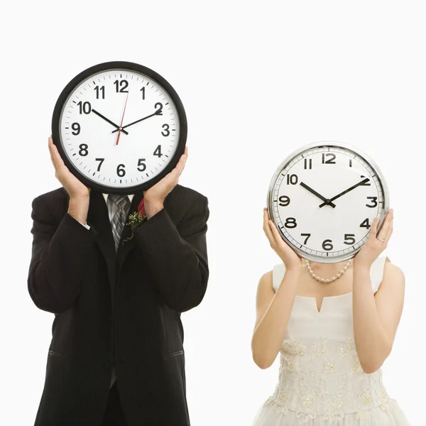 Bride and groom with clocks. — Stock Photo, Image