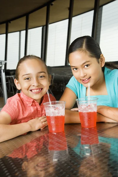 Meninas sentadas e sorrindo com bebidas — Fotografia de Stock