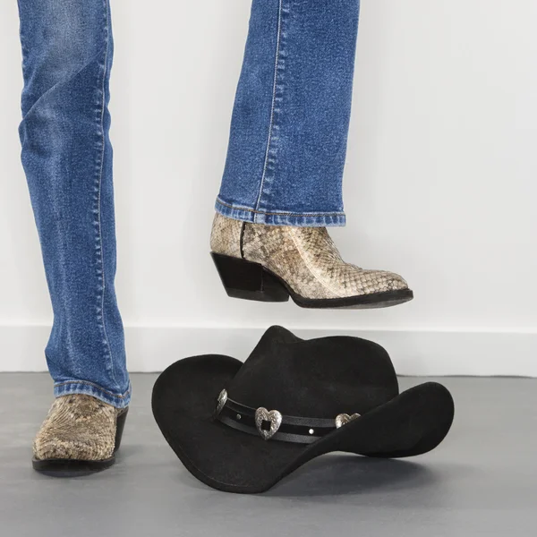 Boots stomping cowboy hat. — Stock Photo, Image