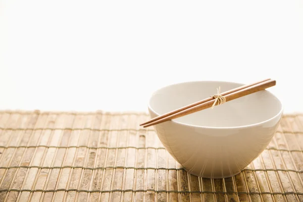 Eetstokjes op een lege bowl. geïsoleerd — Stockfoto