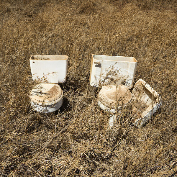 Old toilets in field.