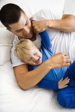 Father tickling son. clipart