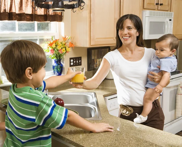 Maminka a děti v kuchyni. — Stock fotografie