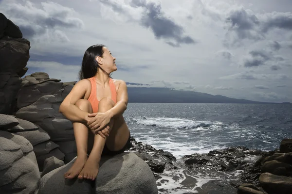 Woman sitting by ocean — Stock Photo, Image