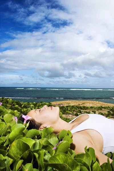 ビーチ近くの植物で横たわる女 — ストック写真