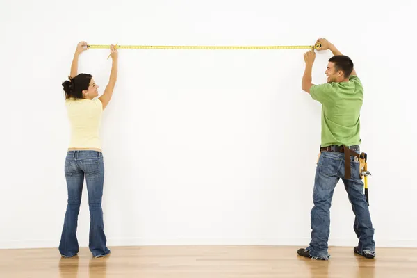 Couple measuring wall. — Stock Photo, Image