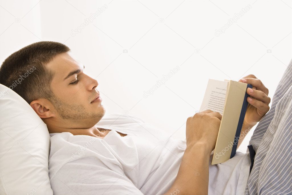 Man reading book in bed.