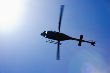 Black helicopter flying overhead. clipart