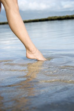 Woman dipping toe in water. clipart