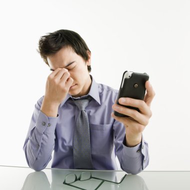 Tired businessman with cell phone. clipart