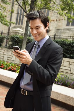 Businessman smiling at cell phone message. clipart