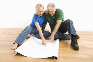 Man and woman looking at blueprints. clipart