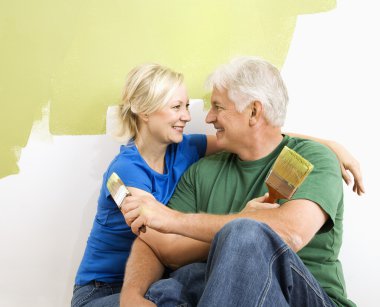 Man and woman snuggling while painting. clipart