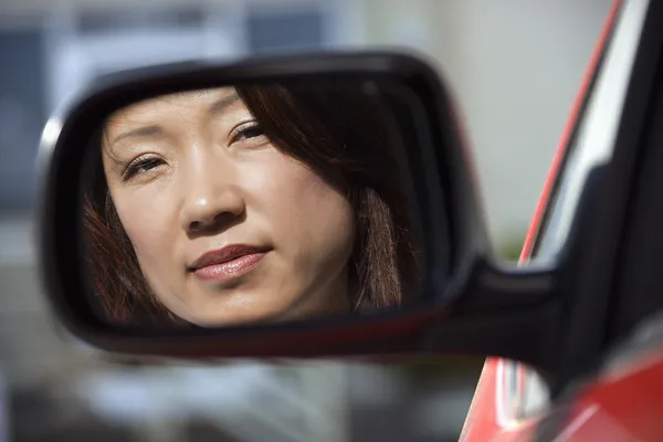 Серьезная женщина в автомобильном зеркале — стоковое фото