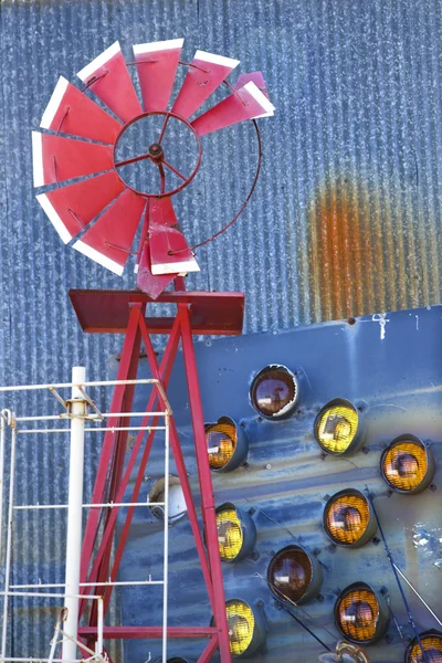 Větrný mlýn proti modré vlnité kovové stavební. — Stock fotografie