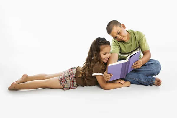 Menino hispânico e menina lendo livro juntos . — Fotografia de Stock