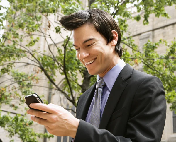 Businessman smiling at cell phone message. — Stock Photo, Image