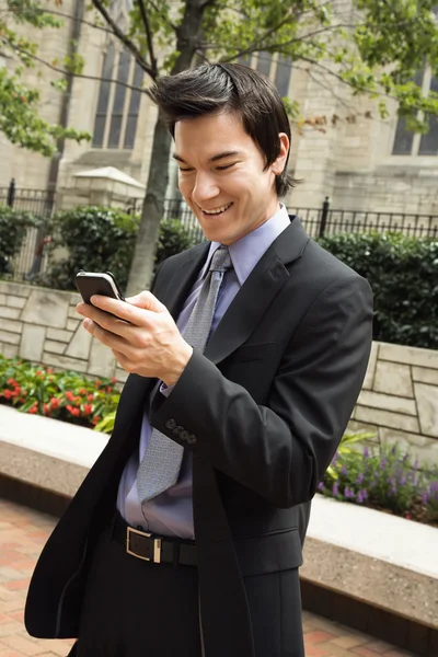 Businessman smiling at cell phone message. — Stock Photo, Image