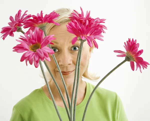 Woman looking through flowers. — Stock Photo, Image