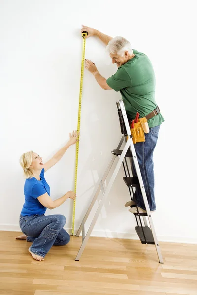 Man and woman measuring wall. — Stock Photo, Image