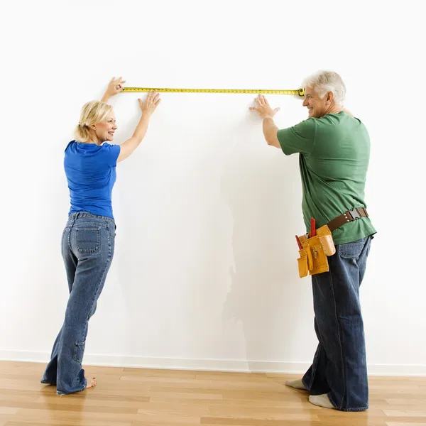 Man and woman measuring wall. — Stock Photo, Image
