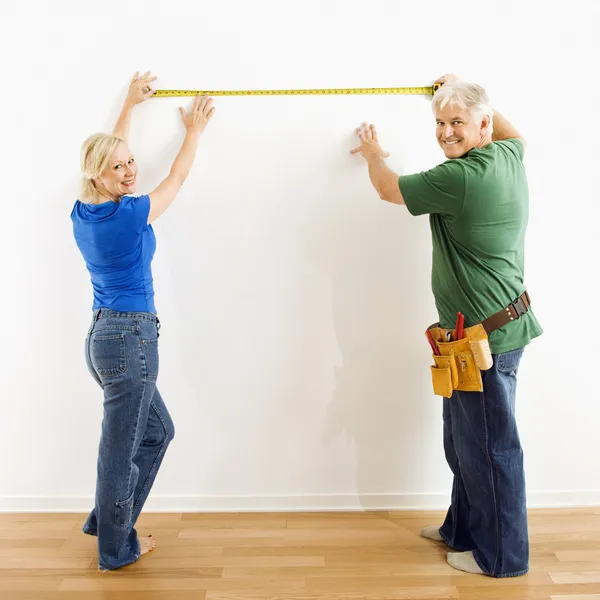 Mann und Frau messen Wand. — Stockfoto