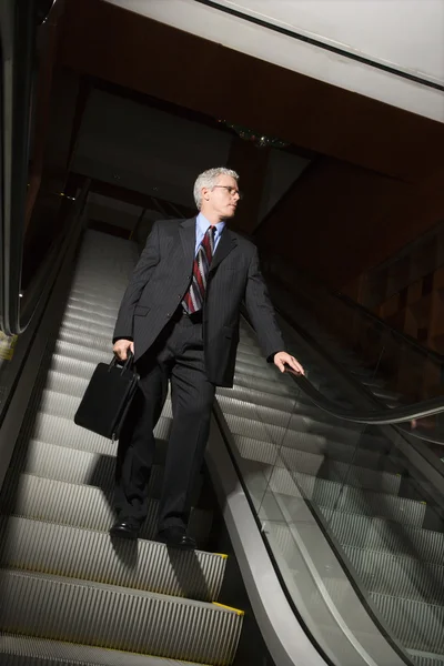 Businessman on escalator. — Stock Photo, Image
