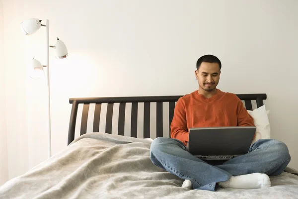 Νεαρός άνδρας στο κρεβάτι, χρησιμοποιώντας φορητό υπολογιστή — Φωτογραφία Αρχείου