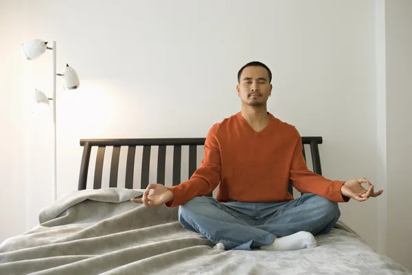 Homem jovem meditando no quarto — Fotografia de Stock