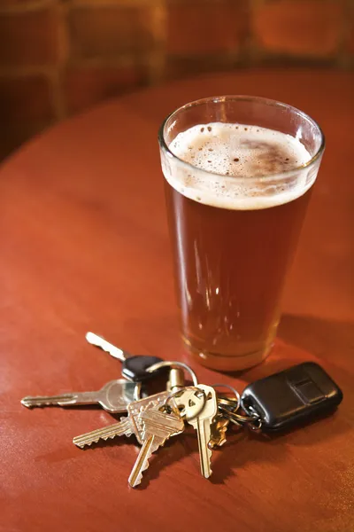 Pohár sör és a kulcsokat a bárpult — Stock Fotó