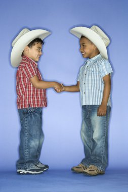 Boys in cowboy hats shaking hands. clipart