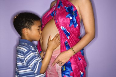 Son kissing mom's pregnant belly. clipart