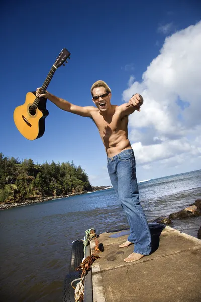 Ενθουσιώδεις νεαρός με κιθάρα στέκεται δίπλα στη λίμνη — Φωτογραφία Αρχείου