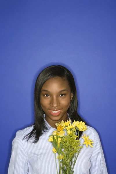 Chica sonriendo sosteniendo flores . — Foto de Stock