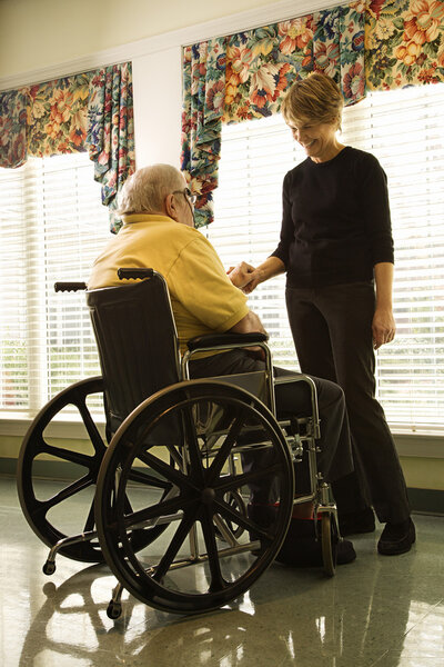 Пожилой человек в инвалидной коляске и молодая женщина

