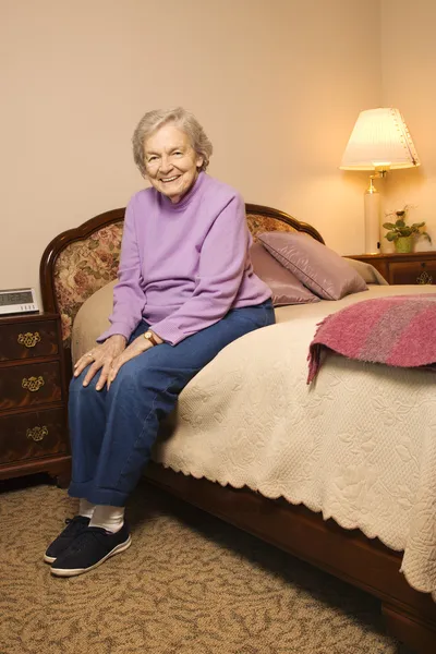 Starsza kobieta na łóżku. — Zdjęcie stockowe