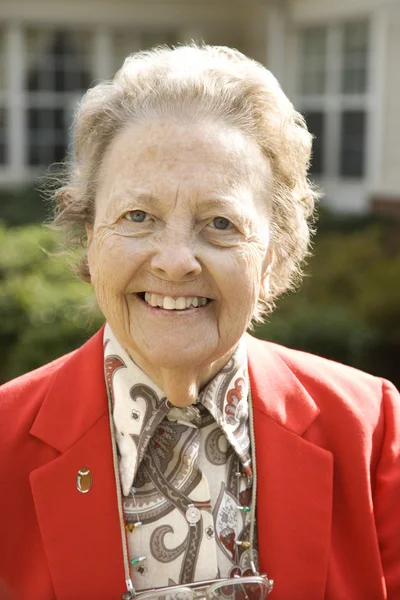 Kırmızı ceketli dışarıda gülümseyen yaşlı kadın — Stok fotoğraf