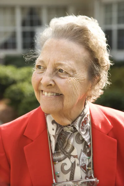 Oudere vrouw in rode jas buitenshuis glimlachen — Stockfoto
