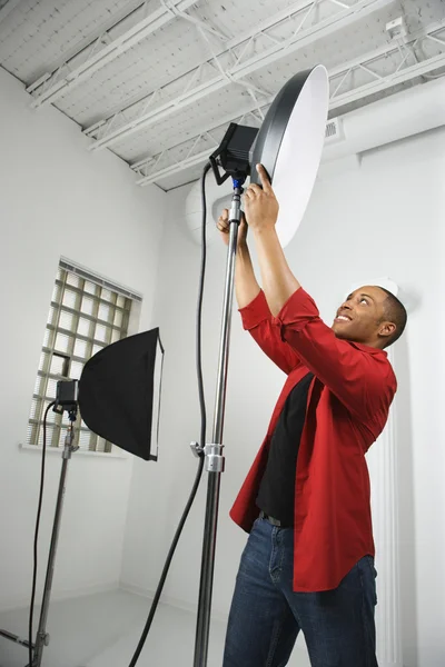 Man adjusting studio lights. — Stock Photo, Image