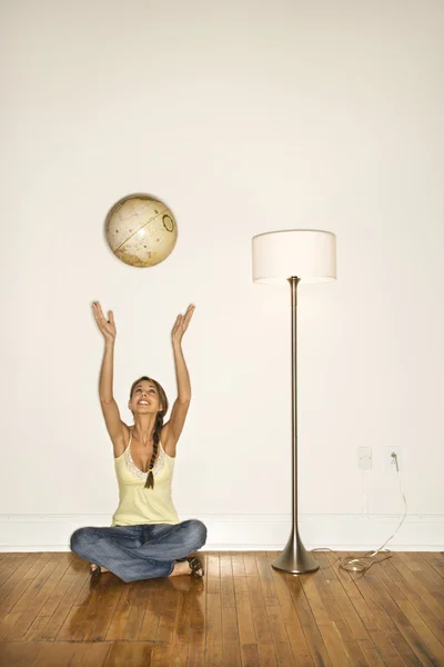 Aantrekkelijke jonge vrouw die lacht en vergadering opgooien van een wereldbol — Stockfoto