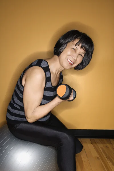 Frau auf Balance-Ball beim Heben von Gewichten — Stockfoto